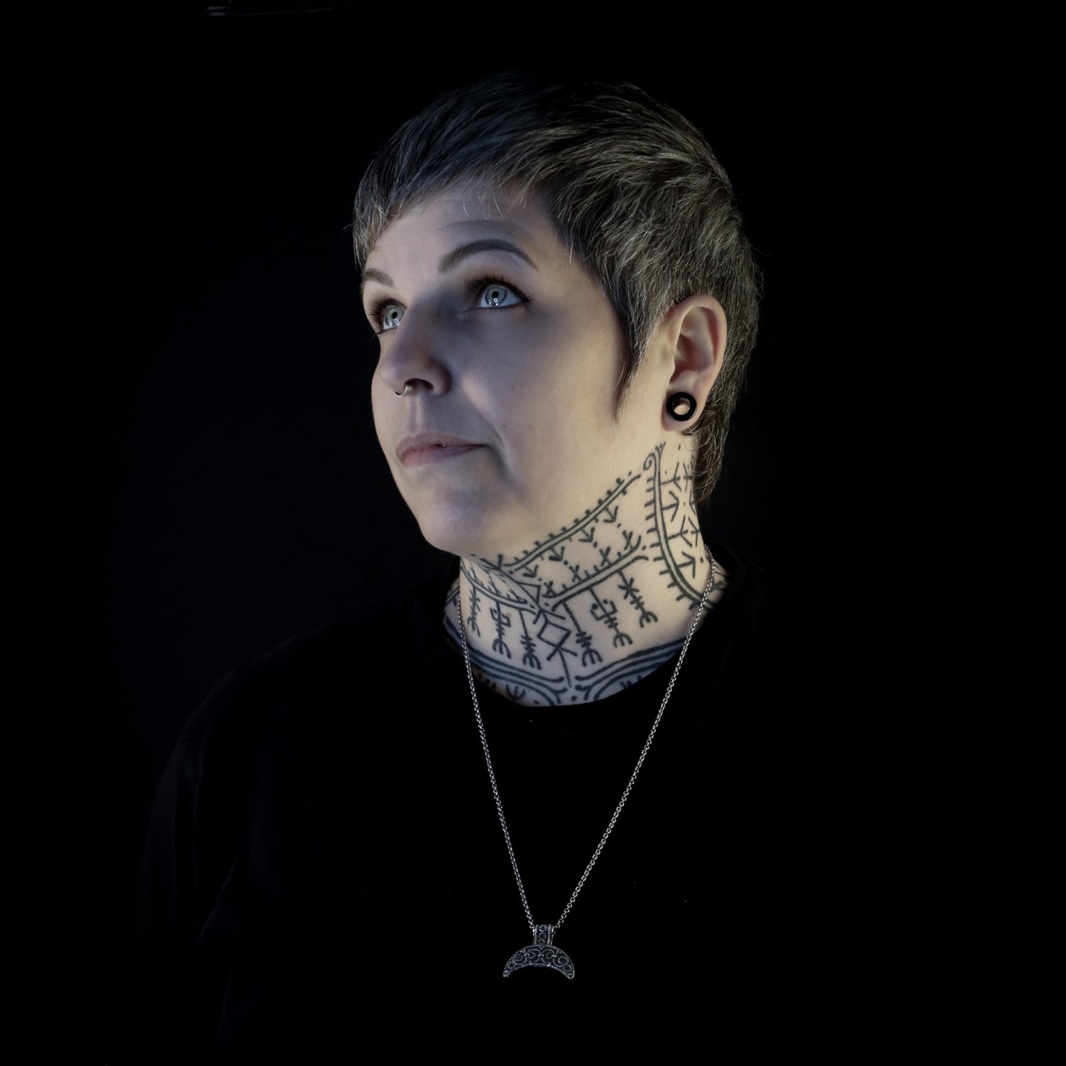 Portrait of Hélène Morrigan, Viking and Norse mythology tattoo artist wearing Nordic jewelry and runic neck tattoo