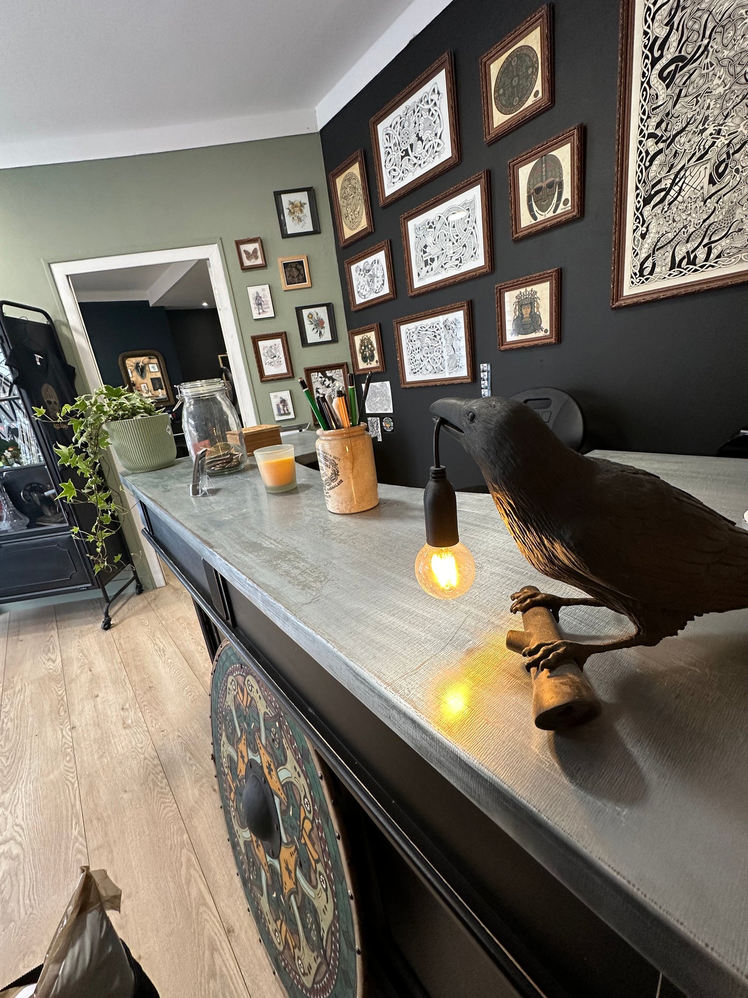 Reception area of Morrigan Tattoo studio featuring Nordic artwork, Viking shield and raven lamp in a Norse-inspired interior design