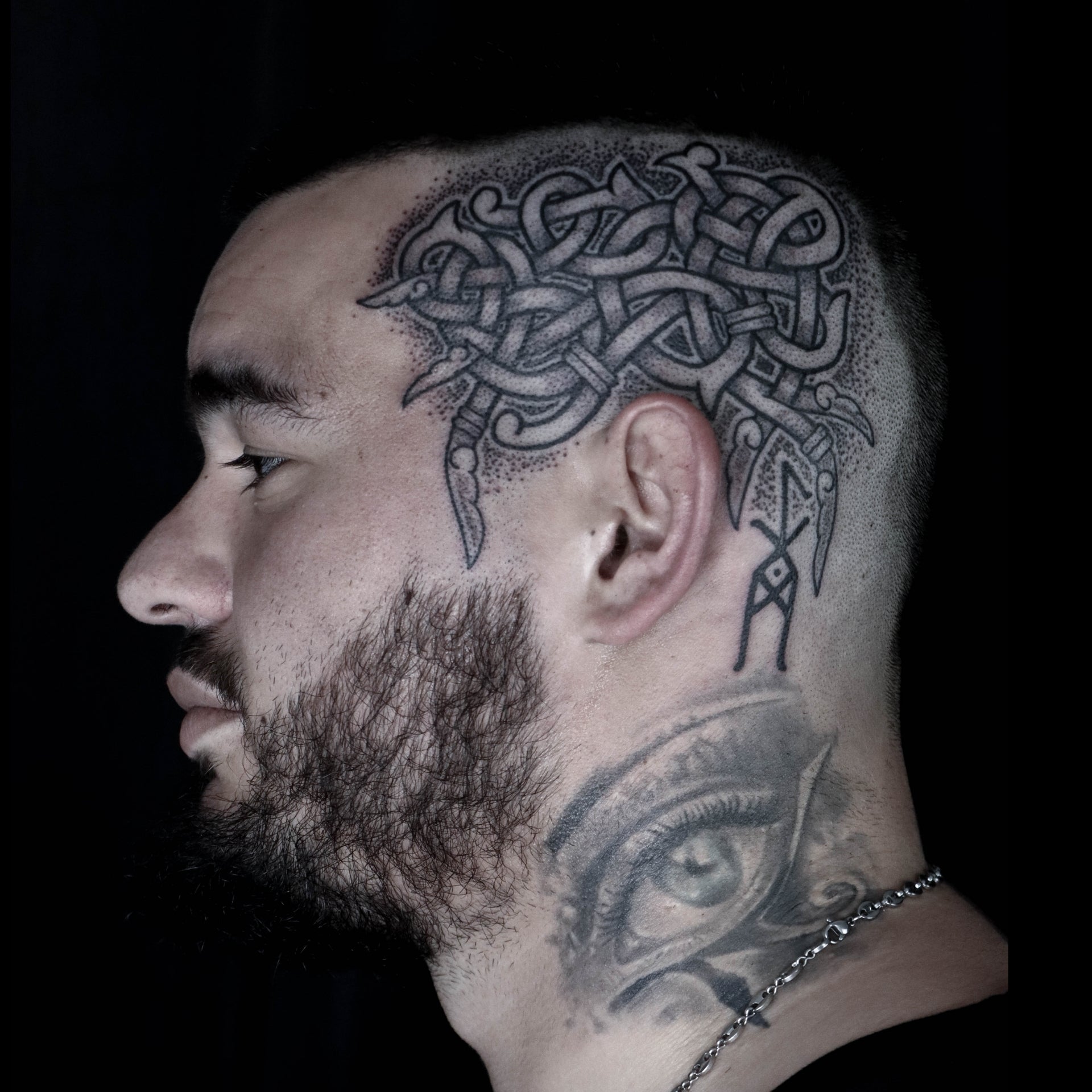 Nordic head tattoo featuring interlaced knotwork with a central bindrune in refined blackwork style