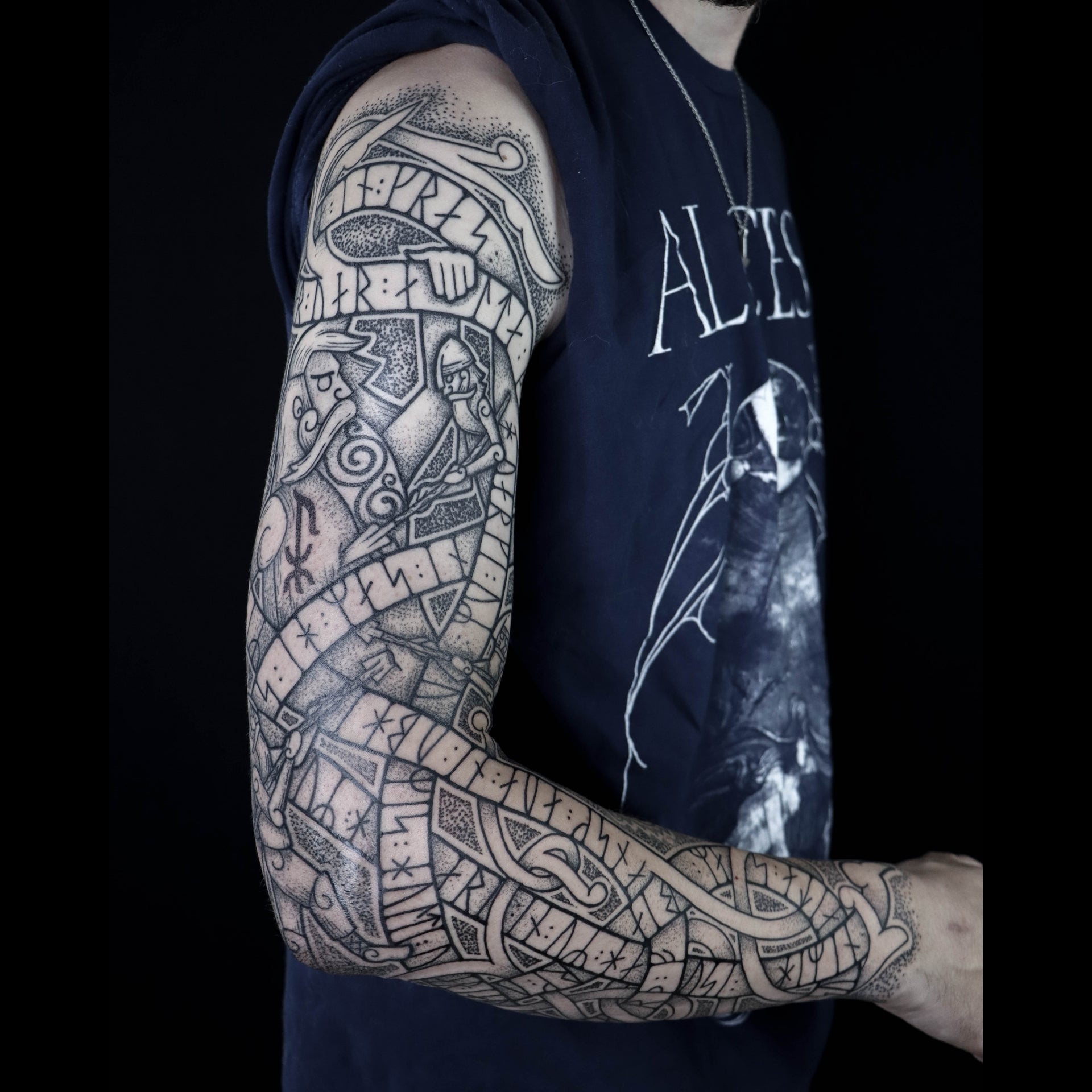 Norse runestone-inspired full sleeve tattoo depicting Ymir slain by Odin, Vili and Vé, surrounded by a wyrm filled with Younger Futhark runic stanza from the Völuspá and intricate knotwork design