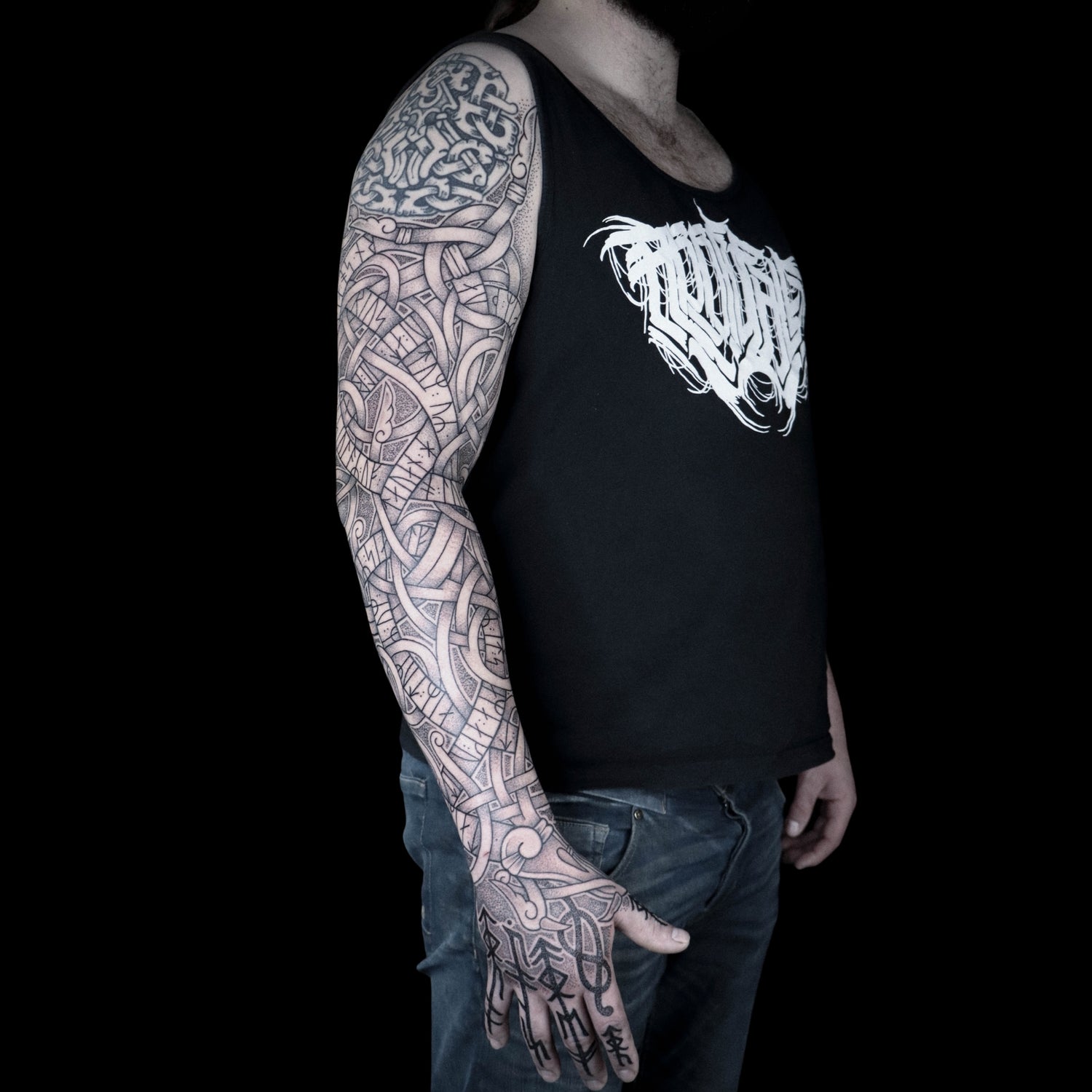 Scandinavian runestone-inspired full sleeve tattoo of Jormungandr with Younger Futhark runic stanza from the Völuspá and bold bindrunes on the fingers in refined blackwork composition