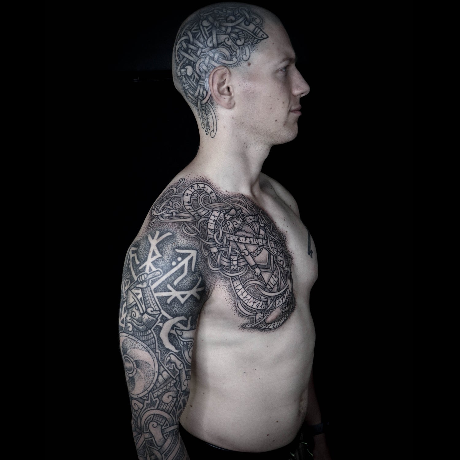 Viking tattoo featuring Fenrir, Odin and a berserker with runic symbols across chest and bicep by Morrigan Tattoo